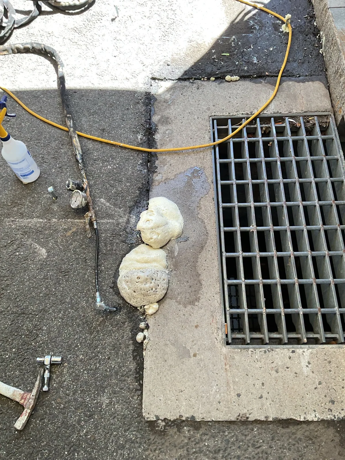 Grout injection ports and hoses beside a catch basin grate