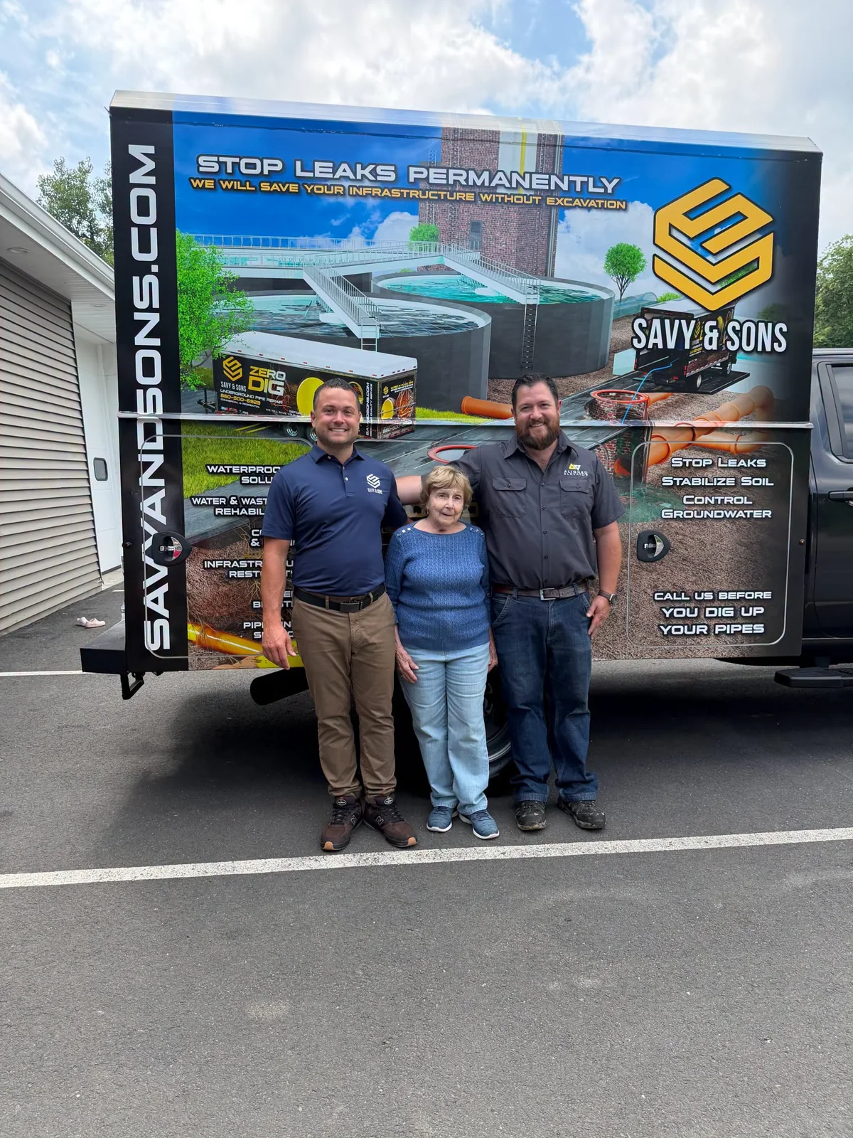 Three adults standing in front of a Savy and Sons branded box truck