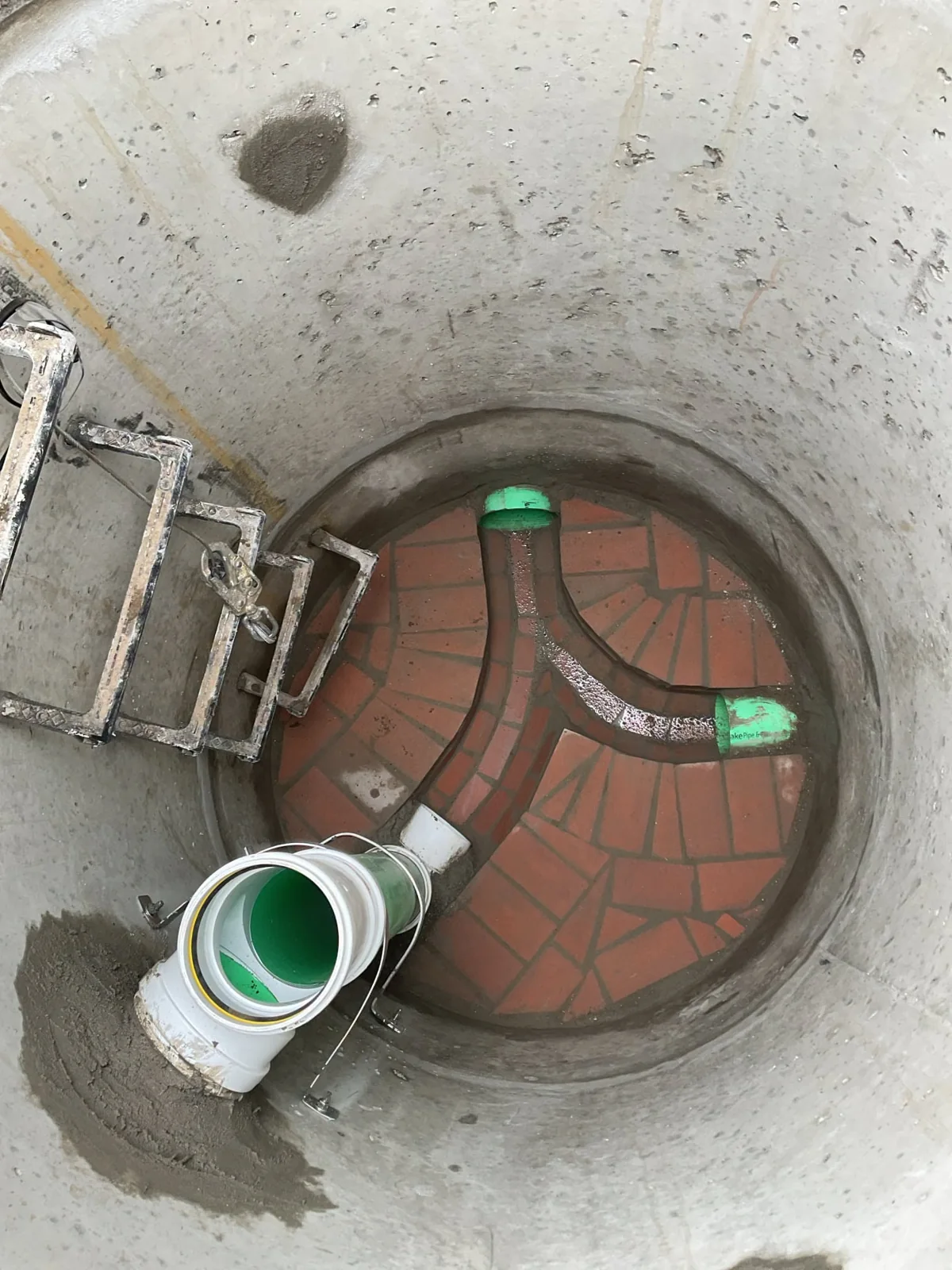 Red brick channels at the base of a manhole with pipe connections