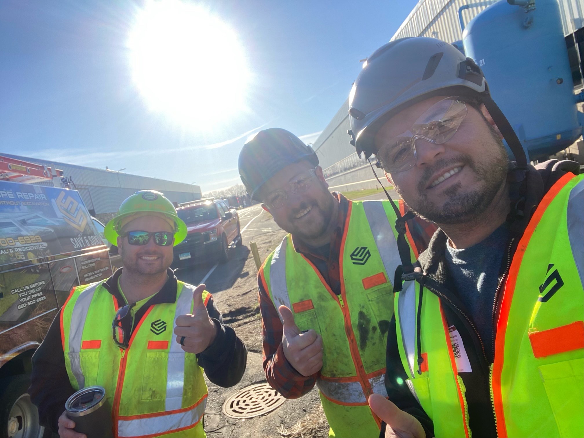 Three Savy & Sons crew members in safety vests and hard hats near a branded service truck