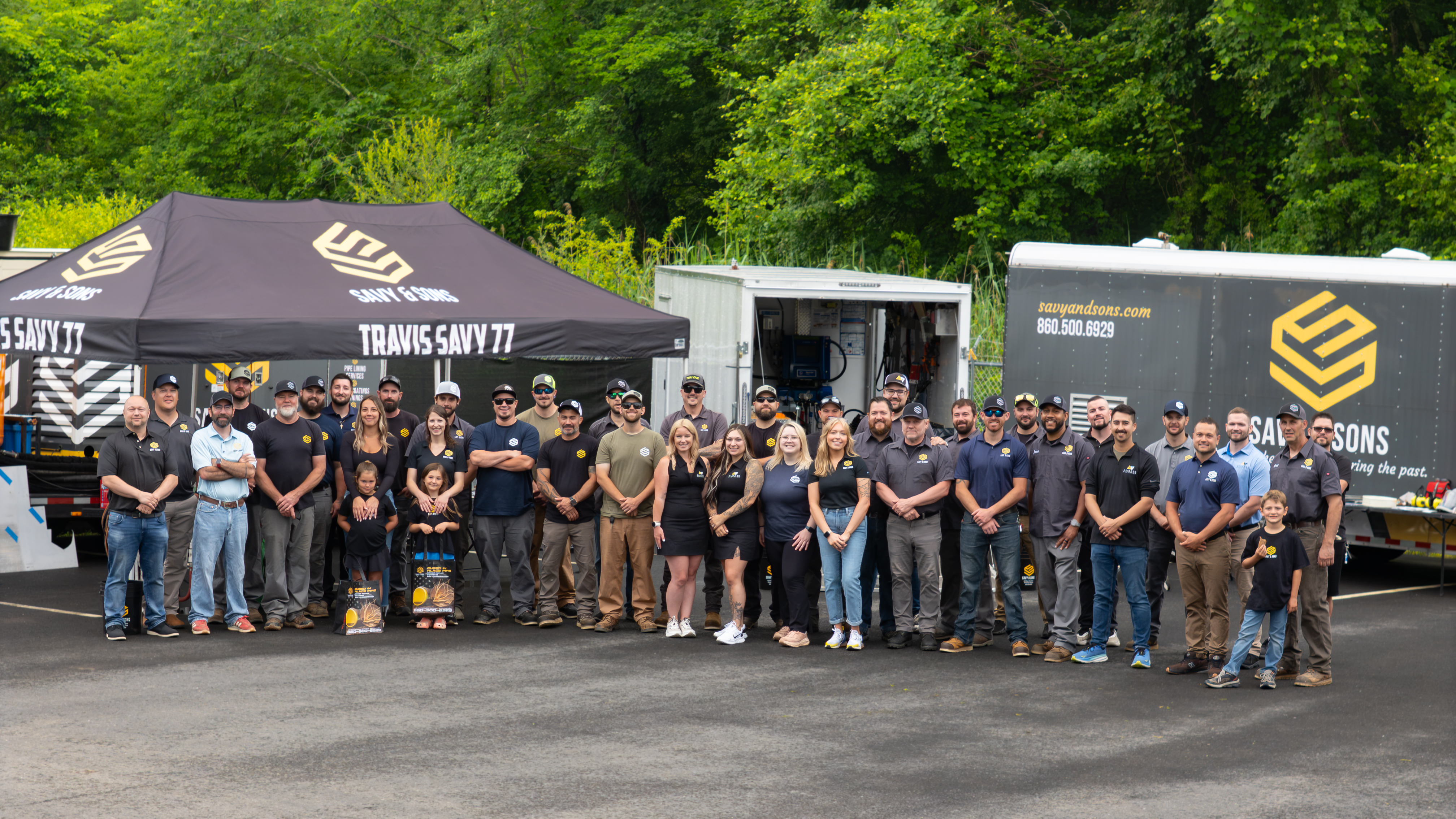 Full Savy & Sons team at company headquarters with branded vehicles and tent